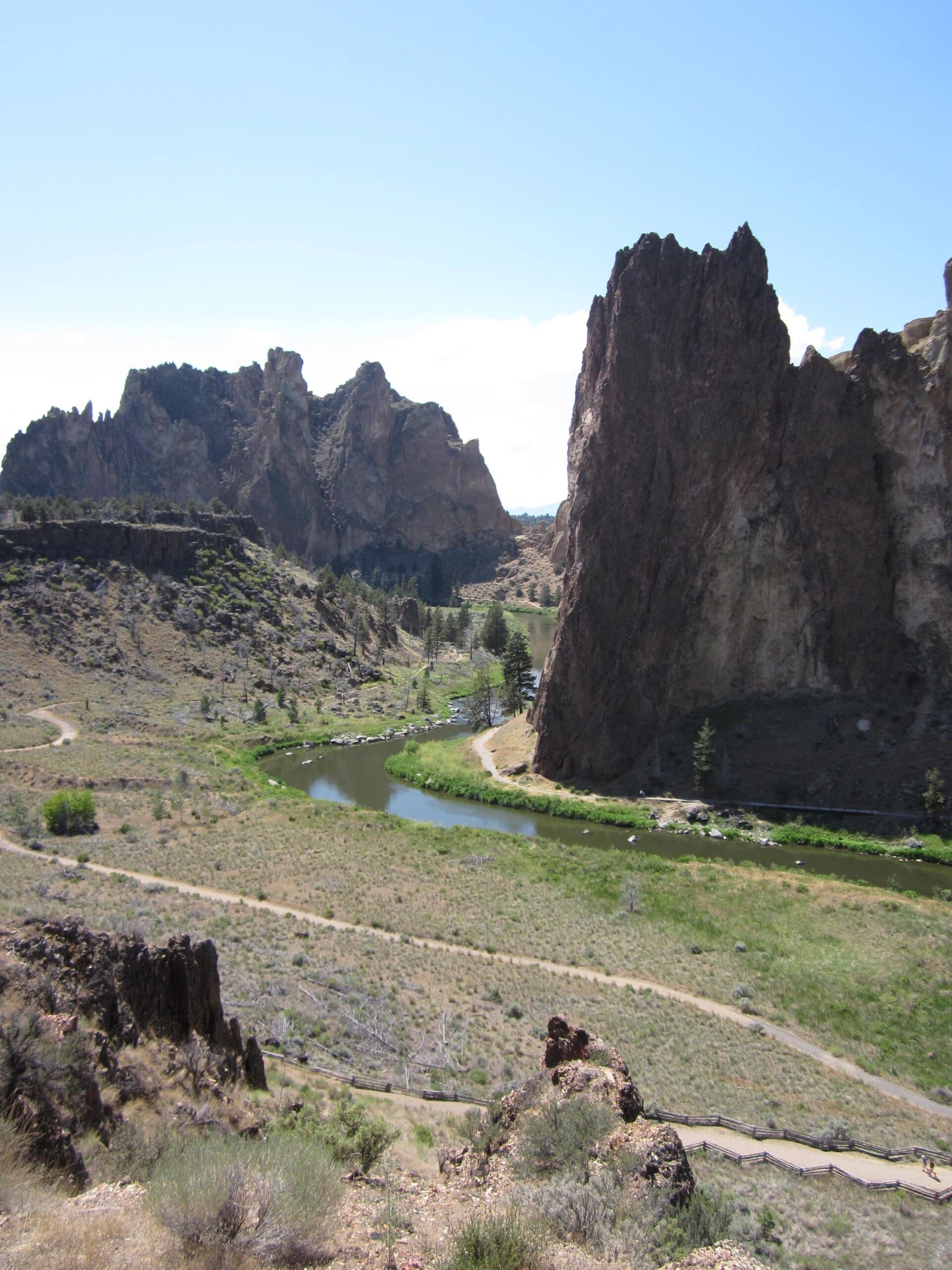 A hiker on a ridge above the high desert with Cascade peaks behind