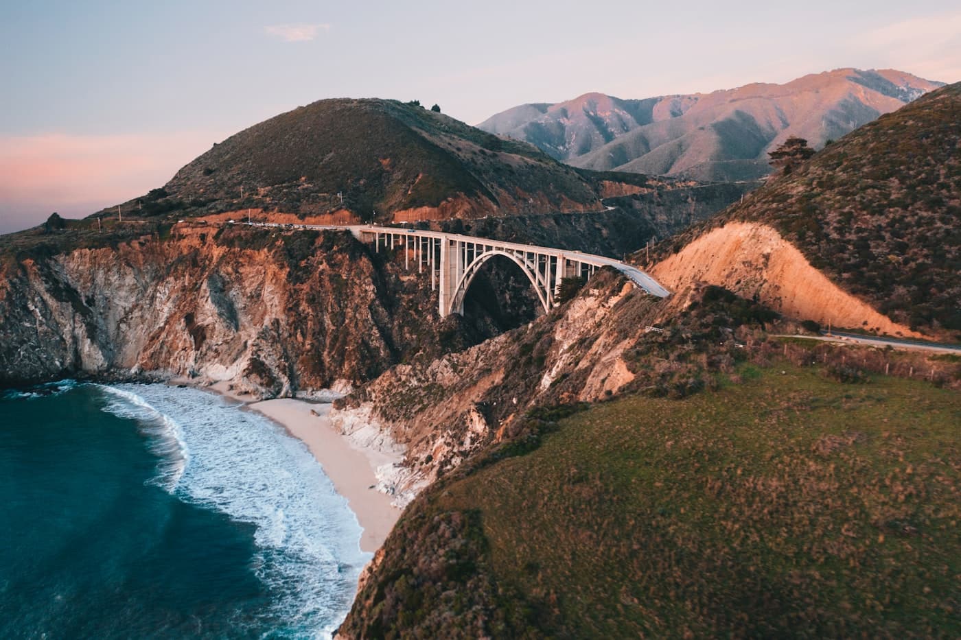 An arched bridge spanning the rugged Big Sur coast at golden hour