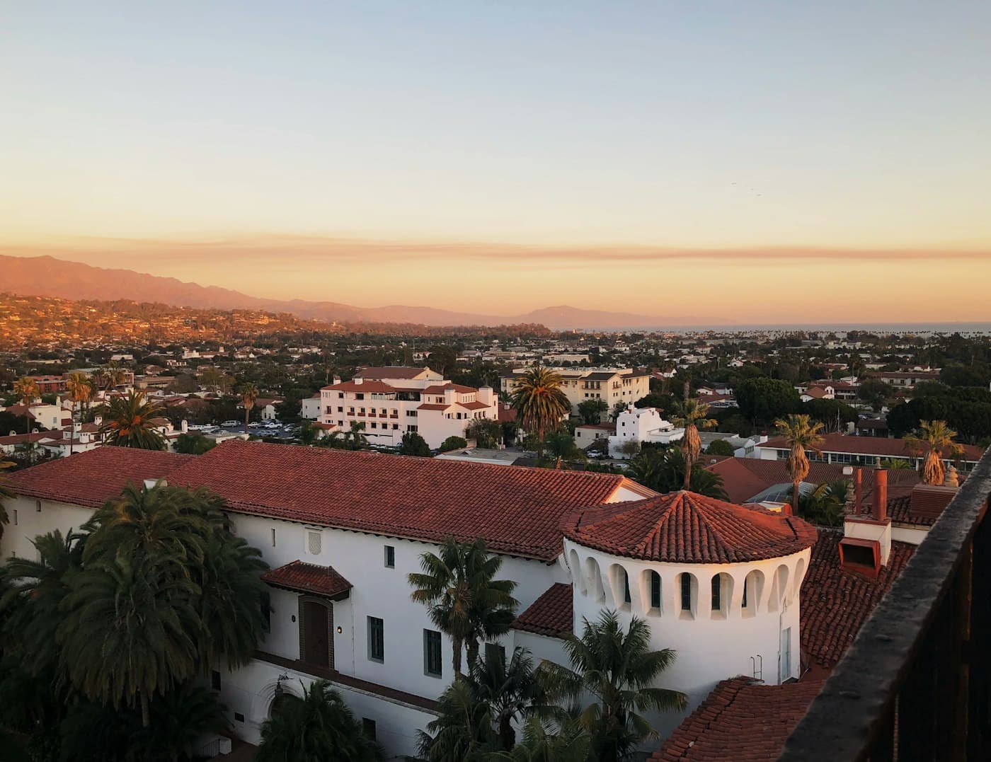Santa Barbara's red-tile rooftops, palms, and coast at golden hour