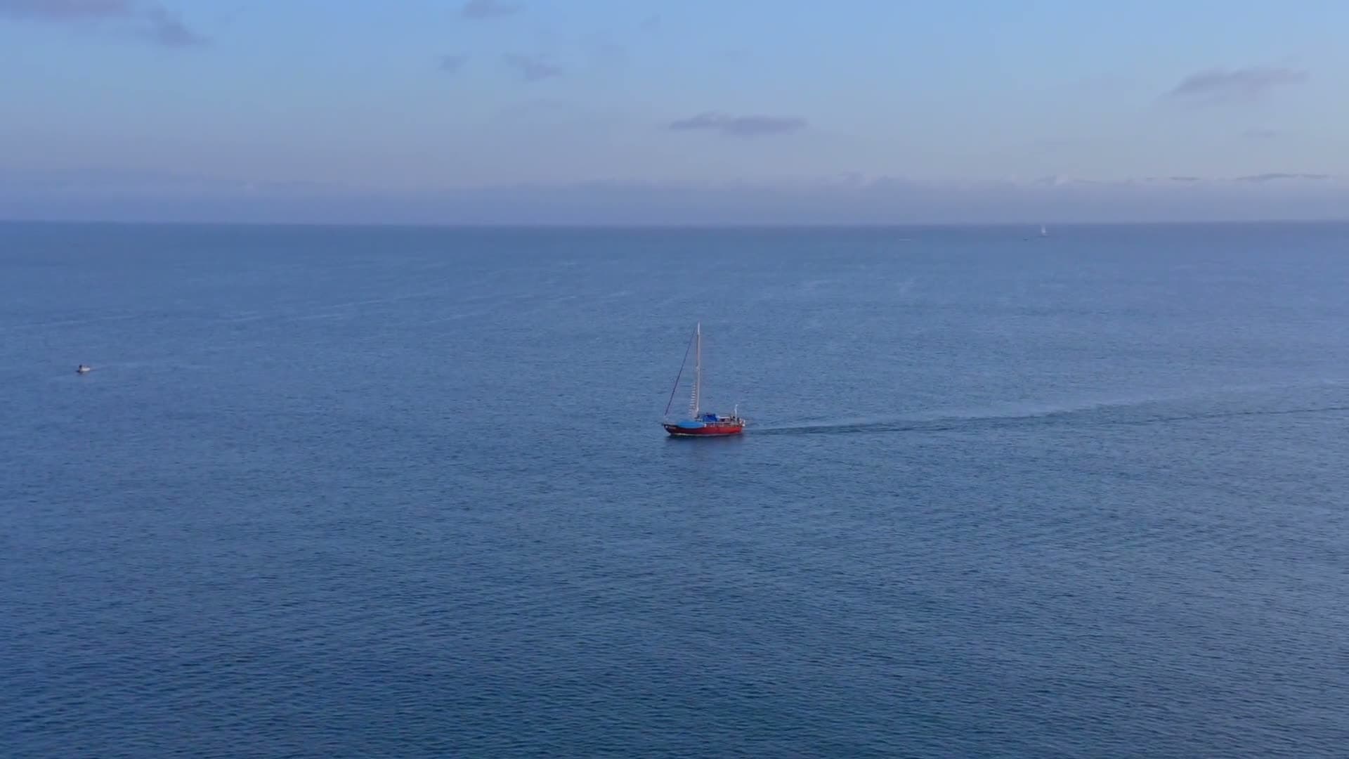 Aerial over a sailing yacht on open blue water